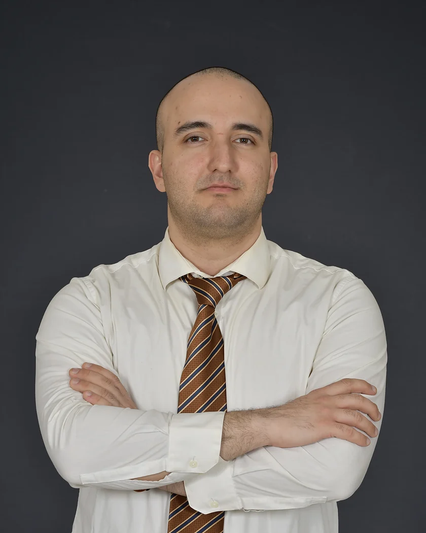 Portrait of Kave Amini Khanimani in a white shirt and striped tie, arms crossed